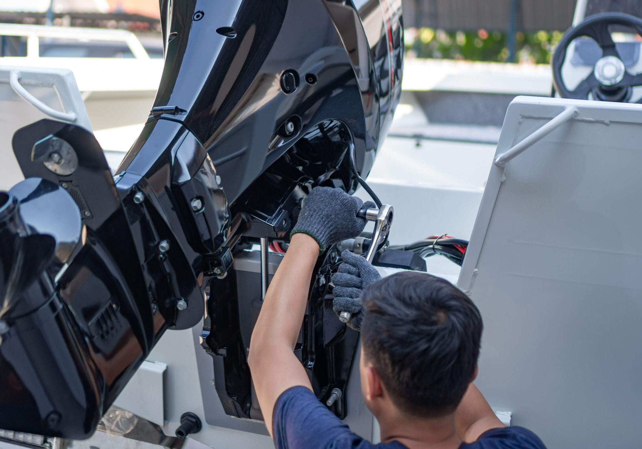 Mechanic is installing speed boat engine , a new engine on an aluminum boat.