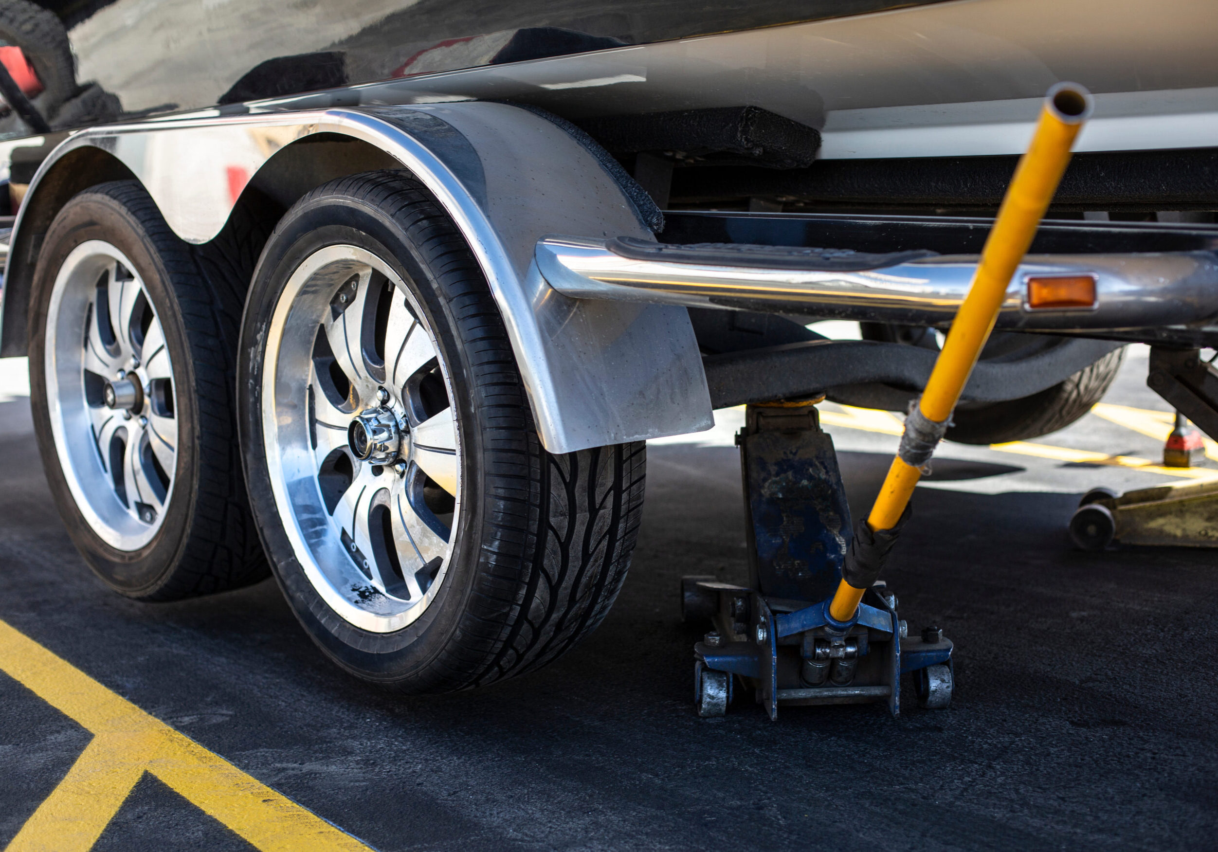 Close up view of a car jack lifting up a boat trailer that just